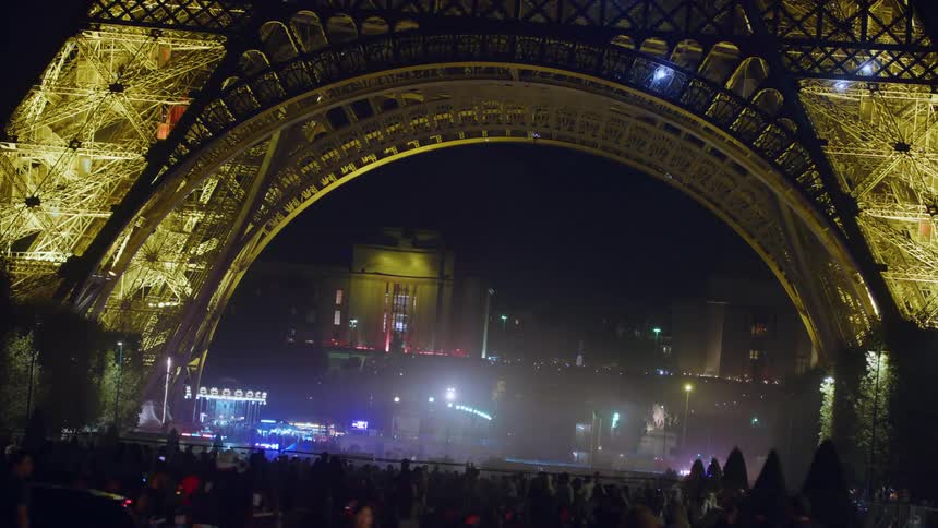 The eiffel tower is illuminated at night by blue flashing lights