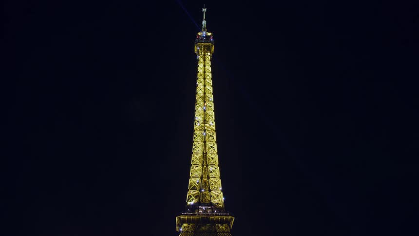 Bright eiffel tower towers over glaring streetlight at night