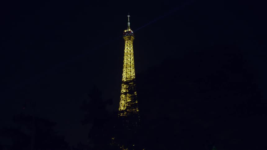 The top of the eiffel tower in paris is all lit up one night