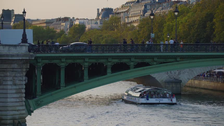 A ferry carries people under the bridge