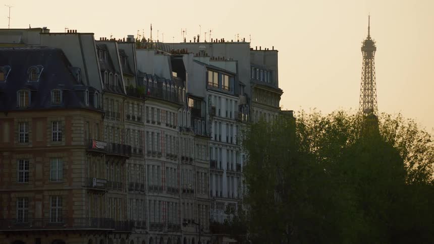 A row of parisian apartment buildings with the eiffel tower visible in the background