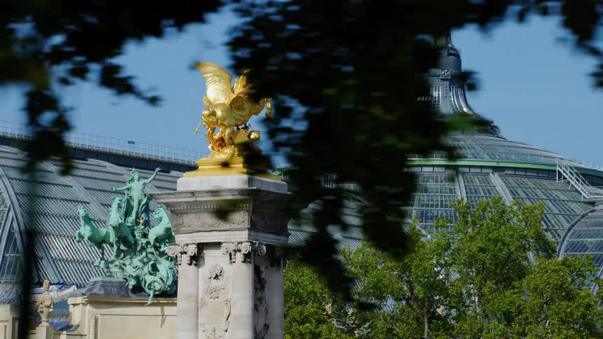 Golden pillar monument next to a building in the middle of the city