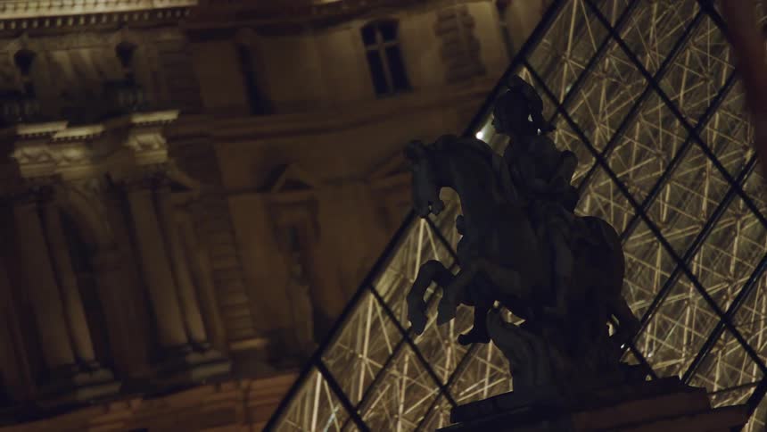 A statue stands in front of a glass building