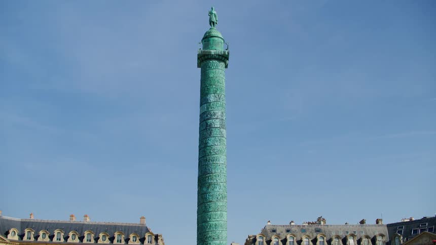 A huge concrete tower with a statue of a person at the top
