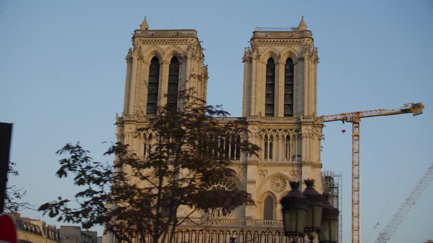 A large building of ancient architecture with two towers and a large crane behind