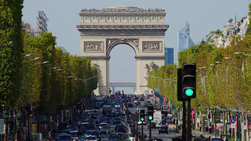 The arc de triomphe stands at the end of a bustling avenue