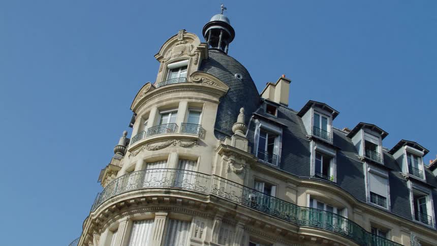 A corner building with old architecture with several windows and balconies