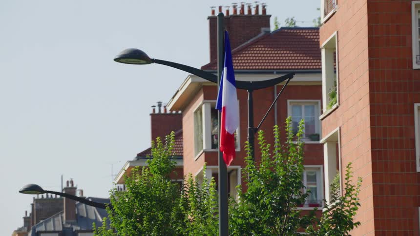 French flag on a pole on the edge of residential buildings