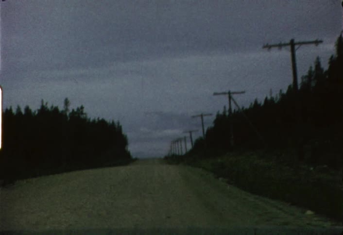 Moving view from a vehicle going down a dirt road as seen through its windshield