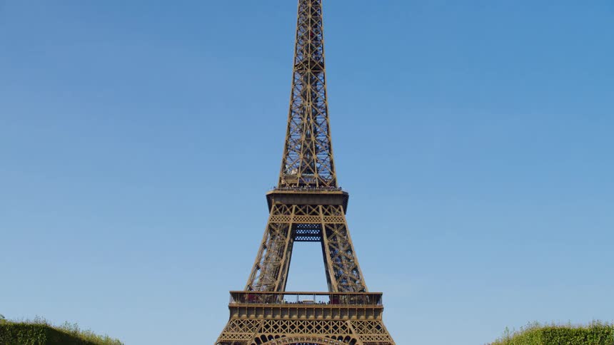 View of the eiffel tower in a square crowded with people on a cloudless blue sky day