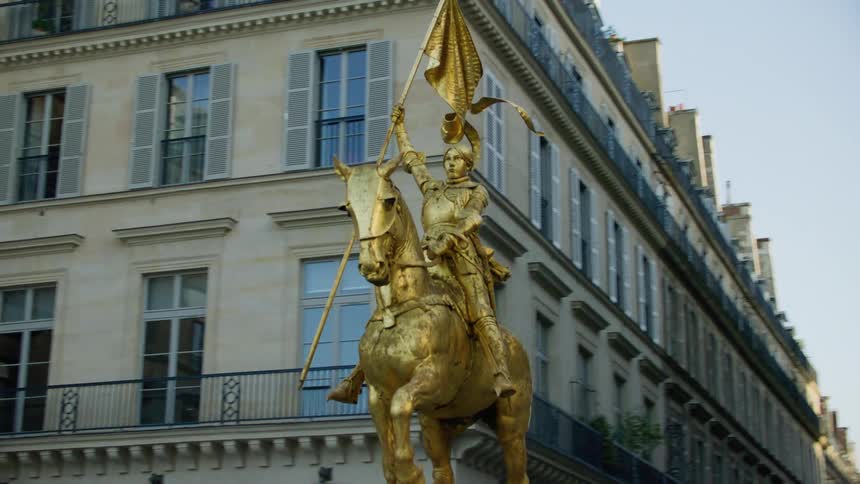 A gold statue is in front of the buildings