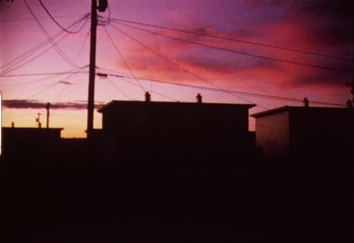 Shaky view of some power lines and houses at a colorful sunset