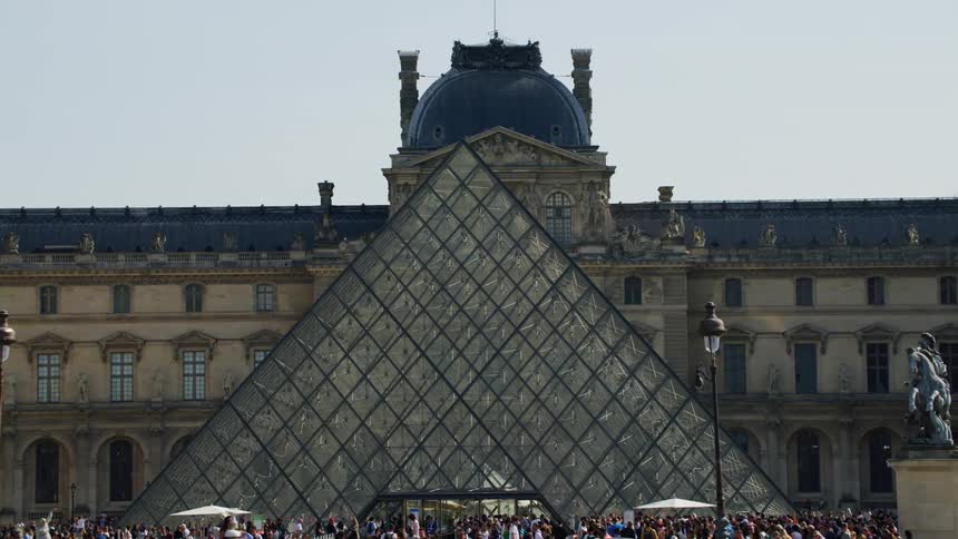 Tourists visit the louvre museum pyramid
