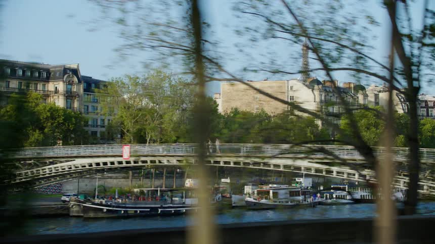 Several buildings and residences facing a river with several boats parked and there is a bridge that crosses both sides