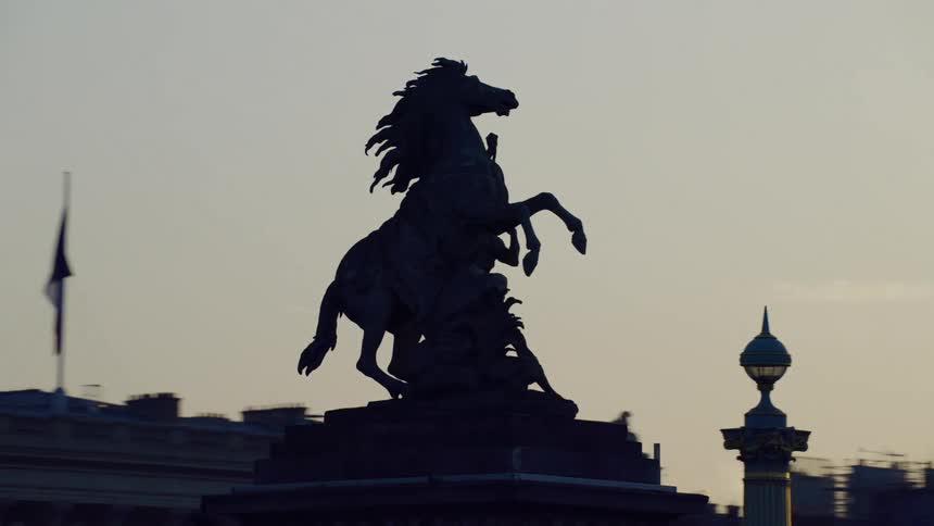 A statue of a horse silhouetted against a sunset sky