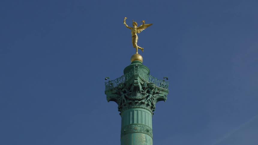 Golden sculpture tops a green column towering over streetlamp