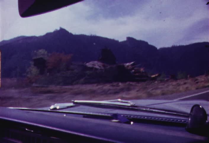 Mountains and roadside as seen through a moving windshield on a cloudy day