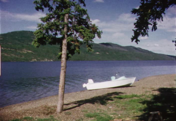 A boat is sitting on the shore of a lake on a cloudy day