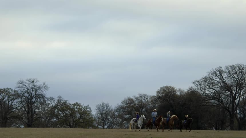 A family is riding horses in a field during the day