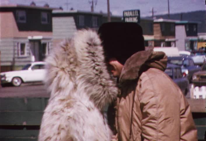 Two people in jackets nuzzling noses together outside