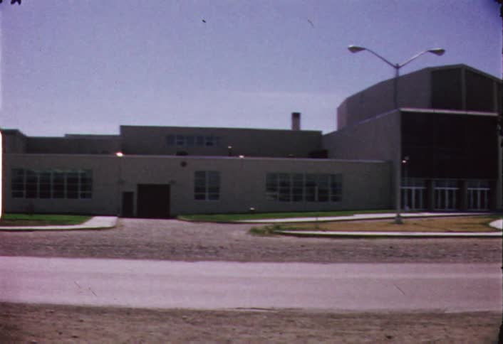 Panning view of a long building as a car passes by