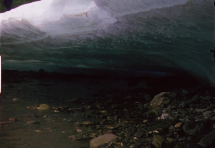 A large block of melting snow drips water on the ground