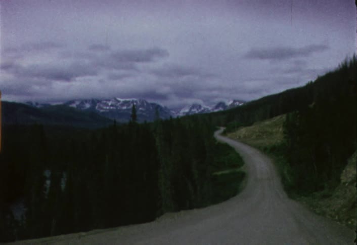 Shaky view of a winding country road on a cloudy day as seen from a moving windshield
