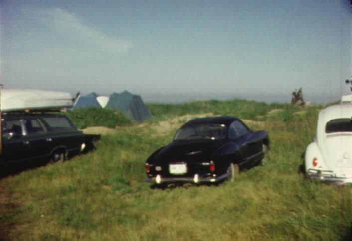 Cars, tents, and campers are parked at campsite on a hill
