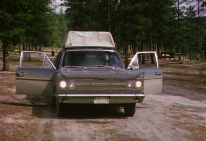 An car with open doors and a person walking behind it