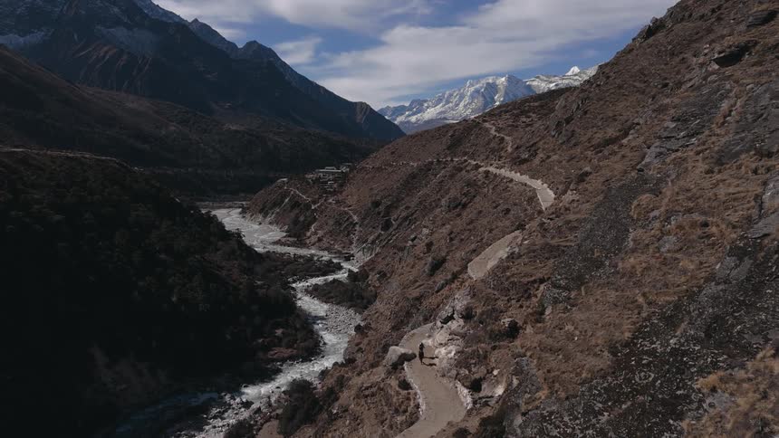 An aerial view of a mountain range with two people walking down a path