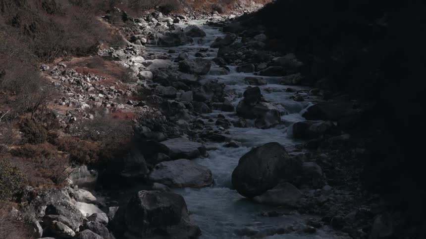 A stream with a strong flow of water and many stones around it and in