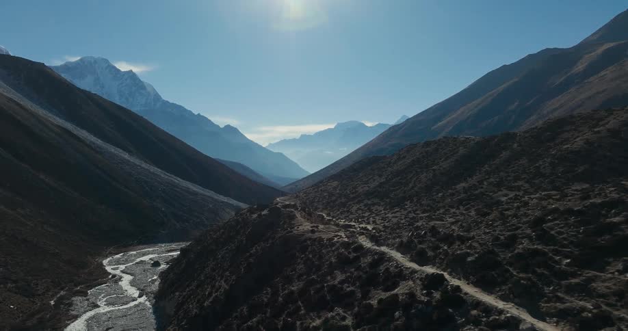 Aerial of a river in the valley and a mountain range in the background