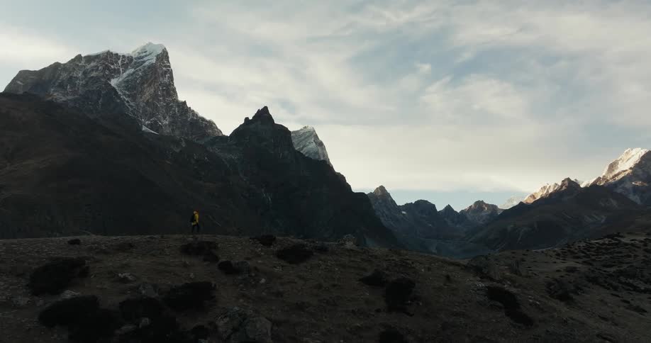 Person walking on a hill surrounded by mountains and blue sky indians with clouds