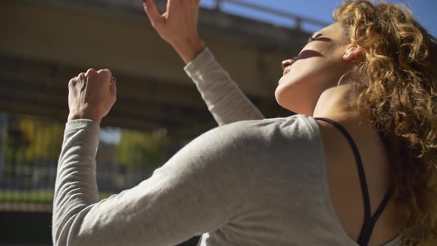 Woman putting hands up to shield her face from bright sun