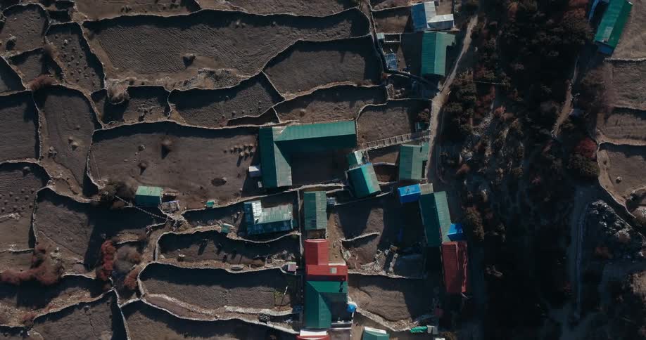 A remote community has several fields and builds with colorful roofs