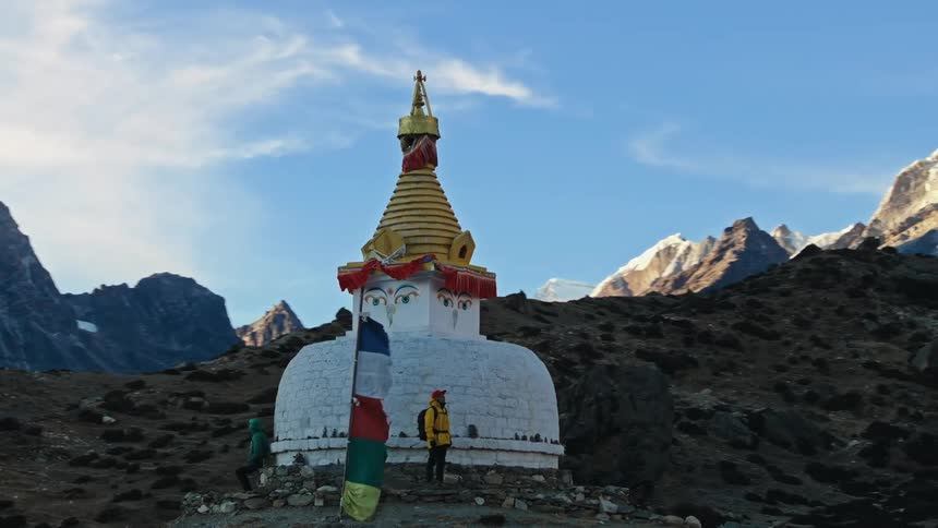 Aerial of a temple in the mountains with people contemplating the landscape