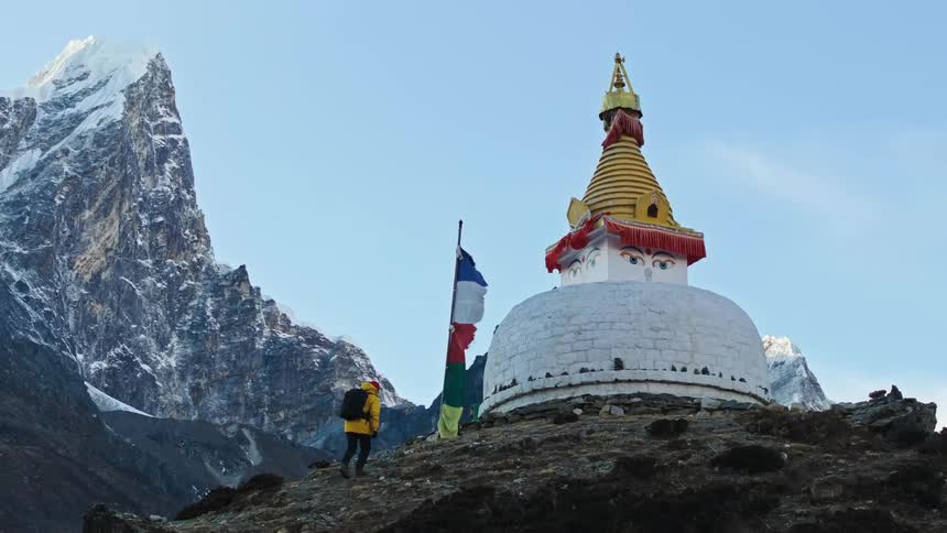 Person walking towards a sanctuary in the middle of a hill surrounded by mountains