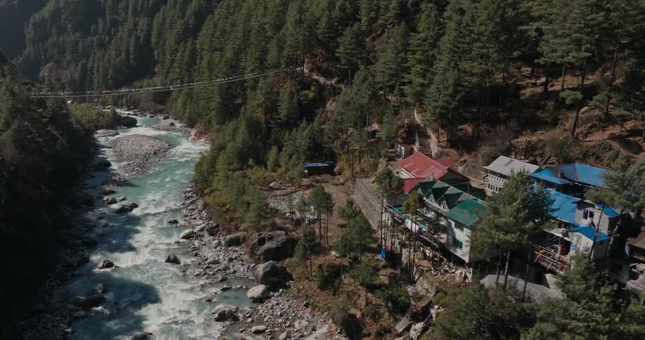 A river carves its way through a forest and past a secluded cluster of buildings