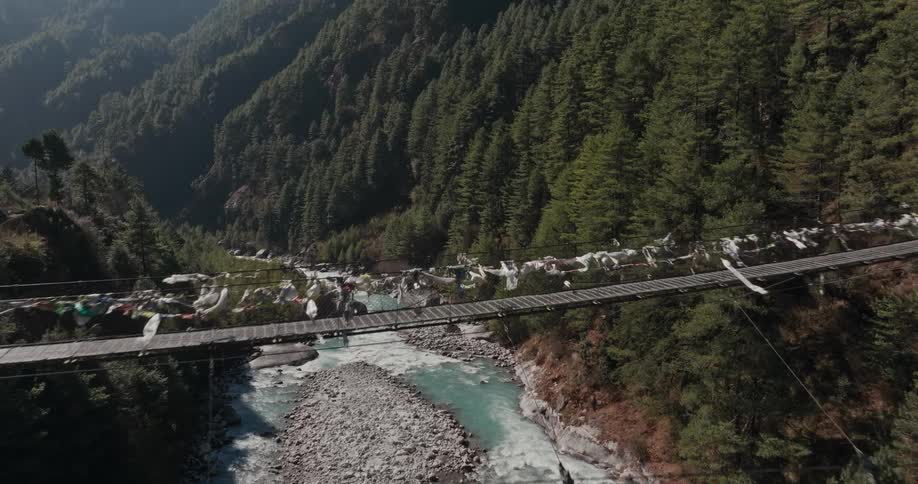 A suspension bridge stretches over a river in a canyon