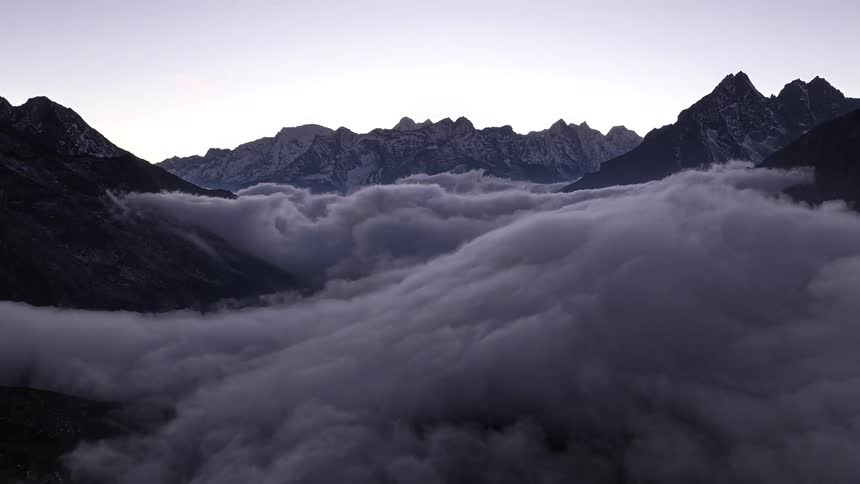 Clouds roil amidst tall mountains