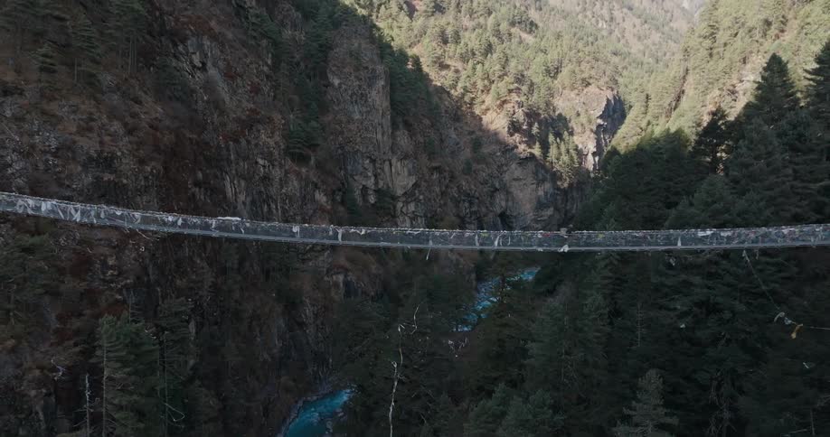 A person runs across a bridge over a deep mountain valley
