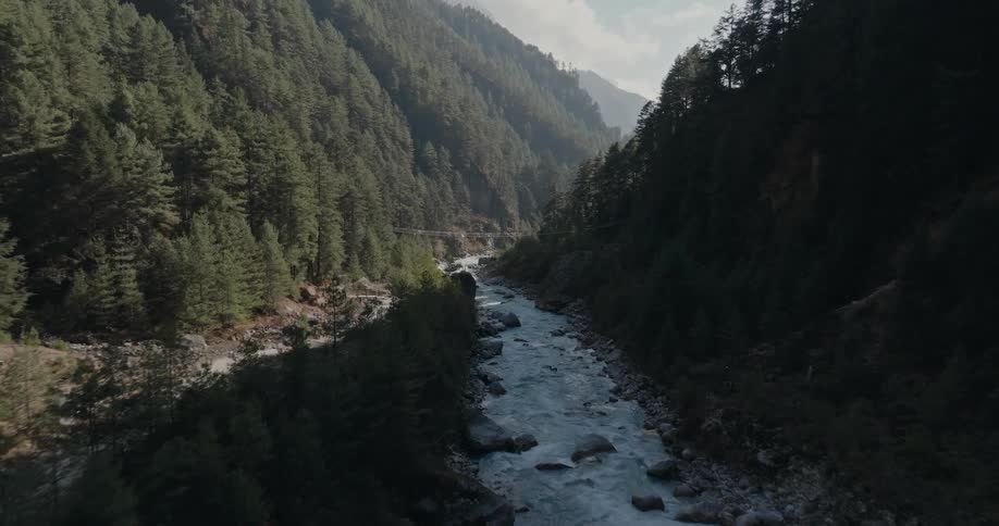 Landscape of a flowing river and a waterfall amid mountains covered in forests