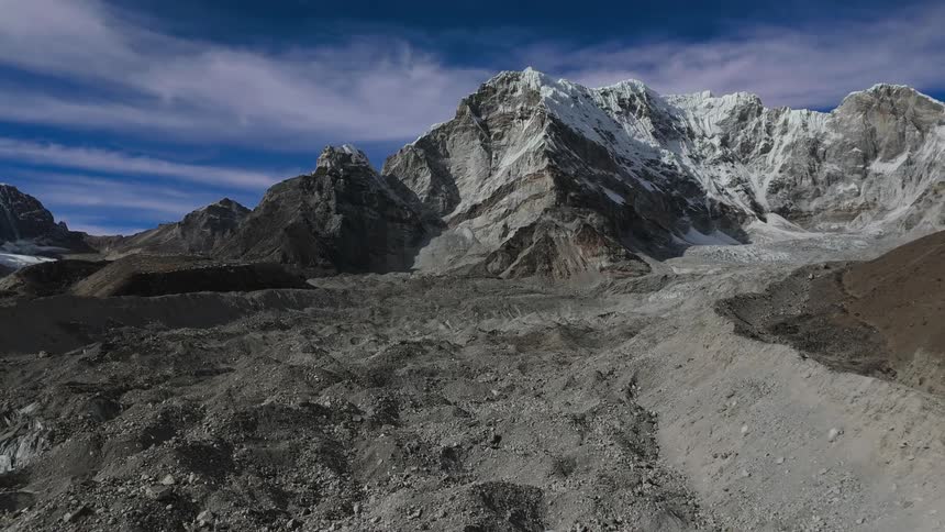 A mountainous region with lots of gravel on the ground and snow on the top of the mountain