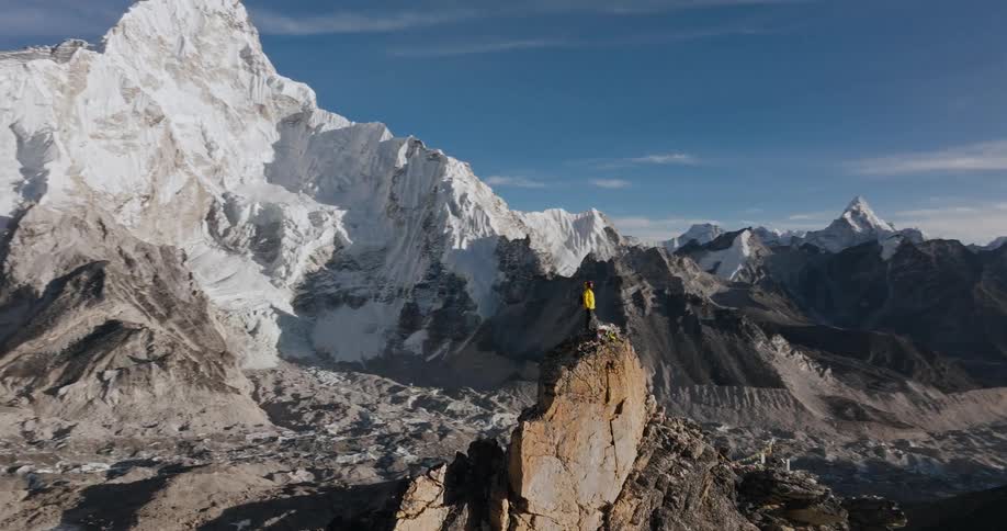 Backpacker stands on ridge in valleysurrounded by mountain range on a cloudy day