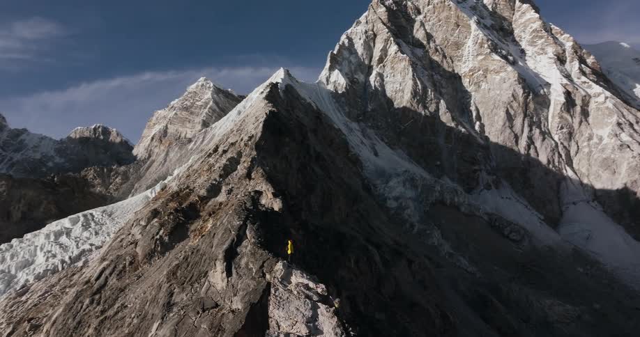 Hikers make their way up a rocky ridge within a mountainlined valley
