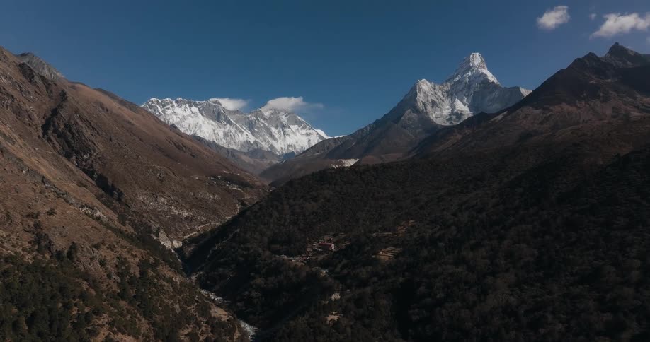 Aerial of a village in the mountains between the river and the forest