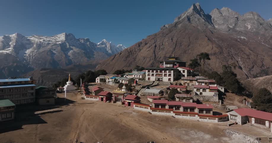 A small town built on top of a mountain and behind it is an even bigger mountain