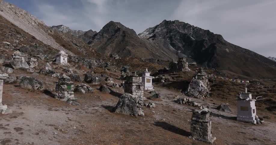 A number of graves sit on a flat area amongst mountains