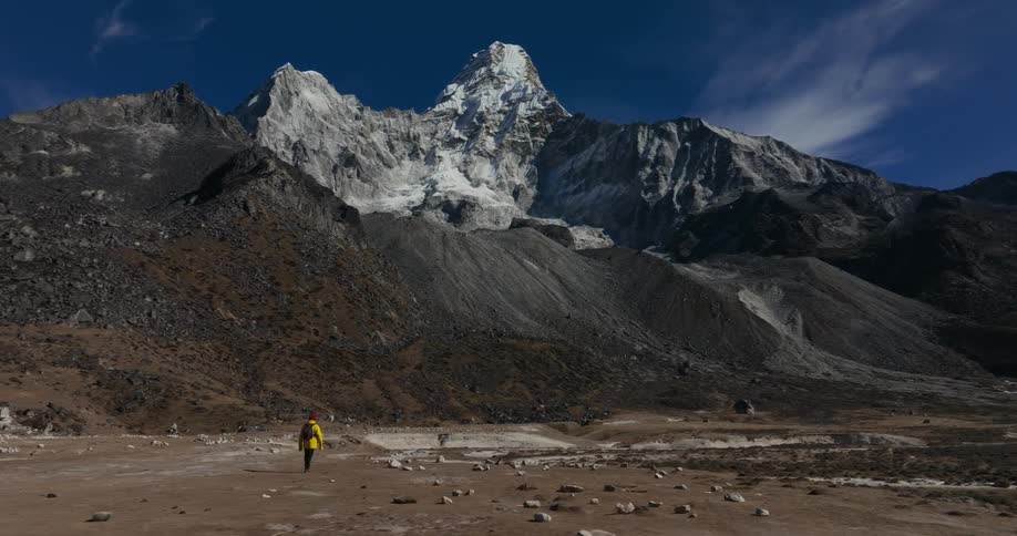 Man walking on a ground surrounded by rocky mountains in winter