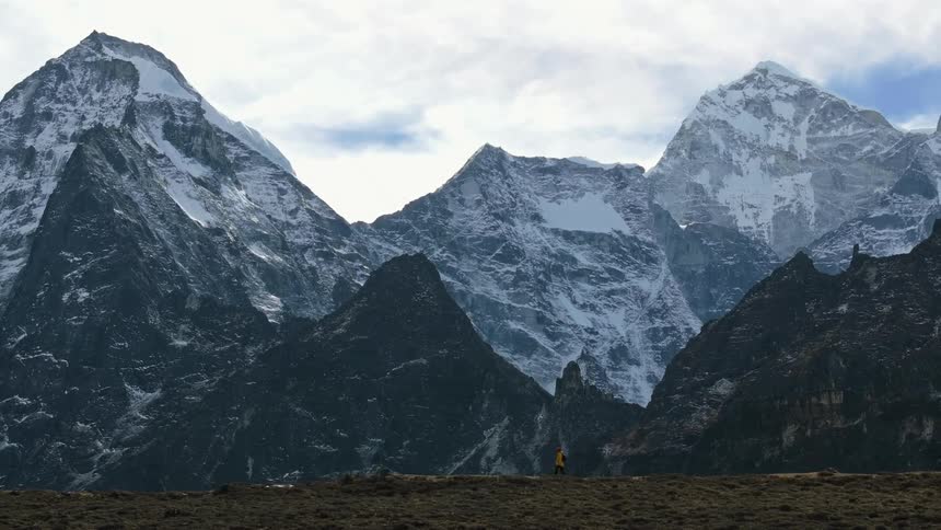 Person hiking on a hill next to snowcovered mountain ranges